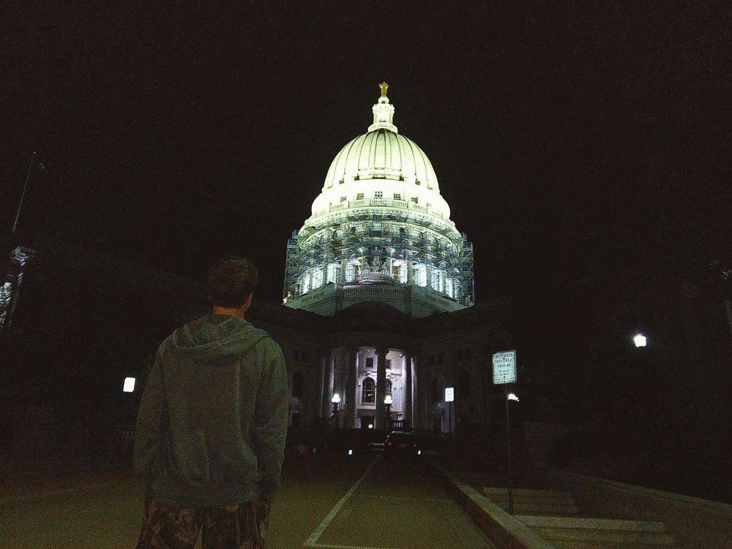 A silhouetted visitor facing an illuminated domed capitol building at night